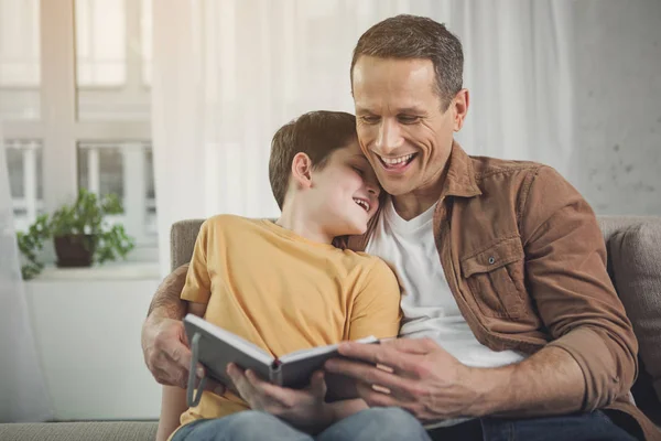 Pai e filho felizes estão envolvidos na literatura em casa — Fotografia de Stock