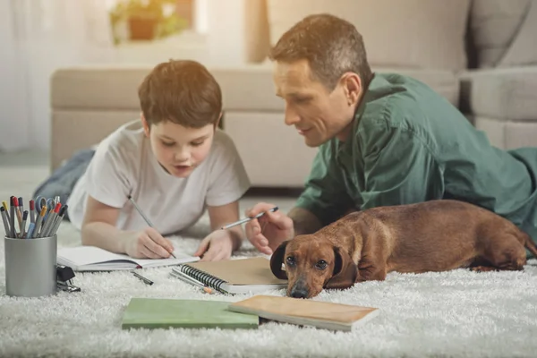 Uinteresseret hund ligger nær travl far og søn - Stock-foto