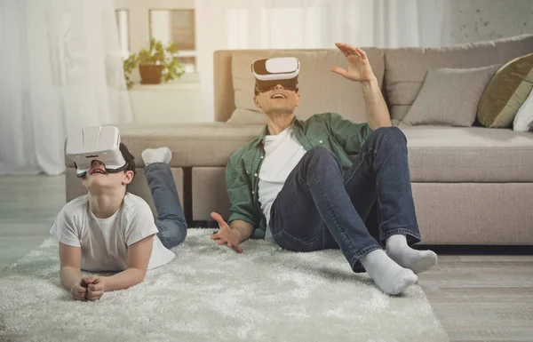 Sorprendidos padre e hijo viendo vídeo en los auriculares de realidad virtual — Foto de Stock