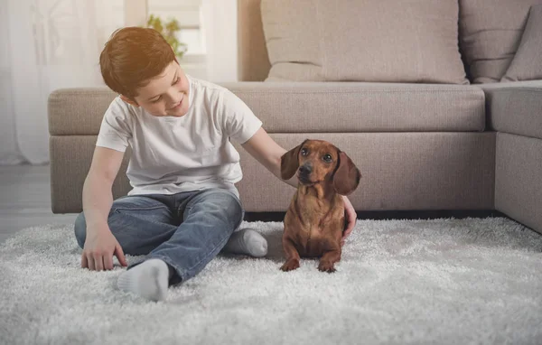 Happy kid playing with puppy in house — Stock Photo, Image