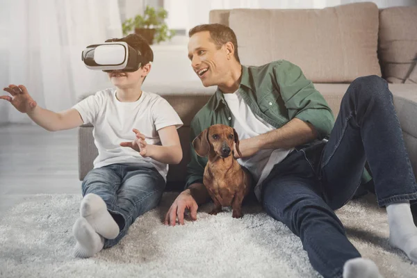 Feliz hijo y papá entretenido con dispositivo moderno en casa — Foto de Stock
