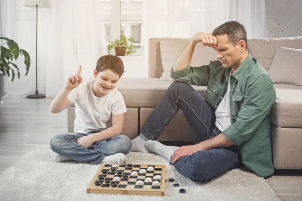 Fröhlicher Sohn gewinnt seinen Vater in intellektuellem Spiel — Stockfoto