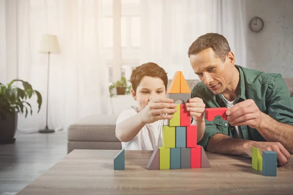 Alegre padre e hijo construyendo torre de bloques en casa — Foto de Stock