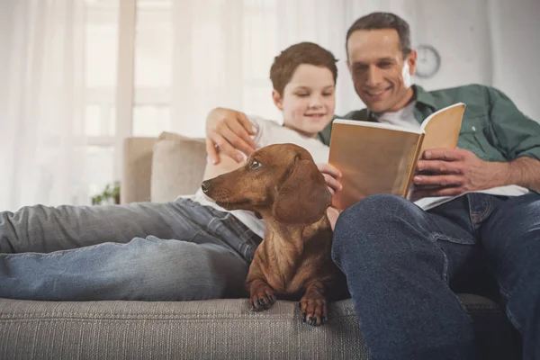 Padre e hijo leyendo libro cerca de cachorro — Foto de Stock