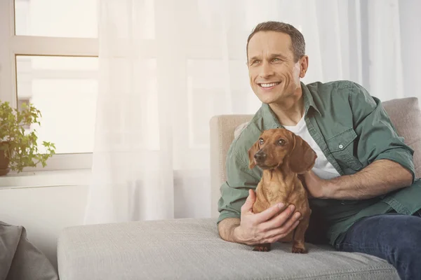 Alegre dueño masculino relajándose en sofá con mascota — Foto de Stock