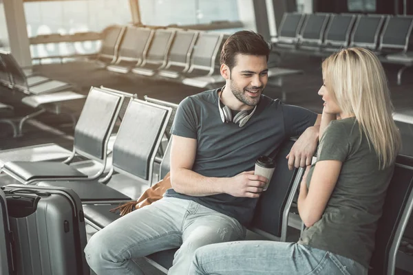 Allegro maschio parlando con una donna positiva in aeroporto — Foto Stock