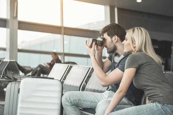 Happy lovers making images by camera in airport — Stock Photo, Image