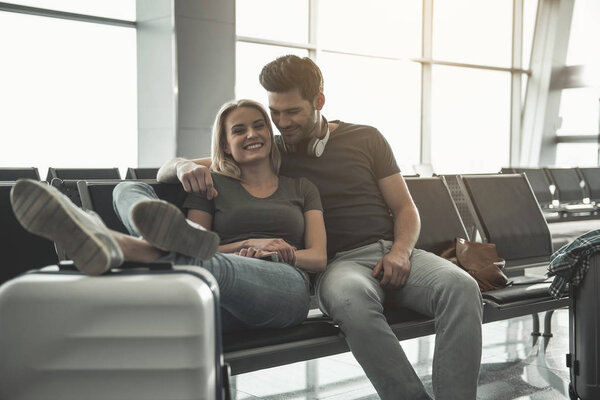 Beaming male embracing outgoing girl in airport