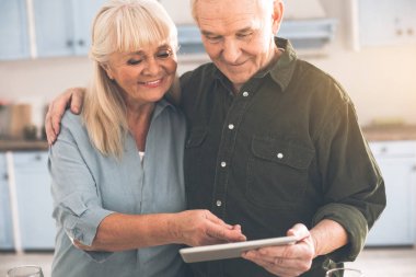 Mutlu eski sevgi dolu çift yemek odasında tablet kullanma