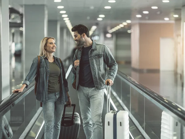 Señorita radiante diciendo con el hombre contento con la maleta — Foto de Stock