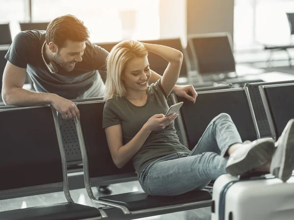 Pareja radiante mirando en el móvil en la sala — Foto de Stock