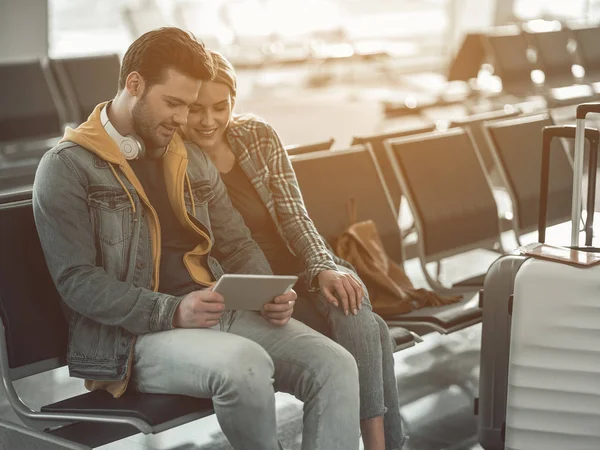 Amantes agradáveis olhando para aparelho no aeroporto — Fotografia de Stock