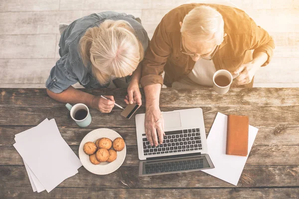 Äldre man att skriva på laptop nära kvinna med kreditkort — Stockfoto