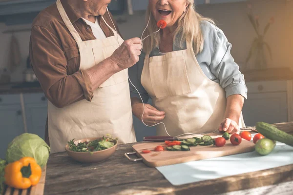 Alegre maduro marido alimentación esposa con vegetal — Foto de Stock