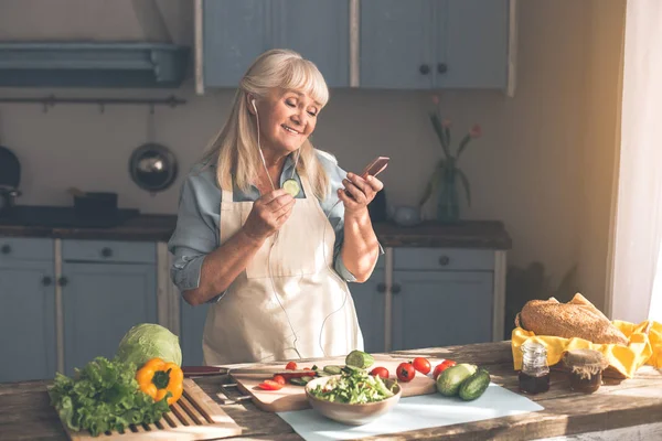 Fröhliche alte Frau wählt Song auf Smartphone — Stockfoto