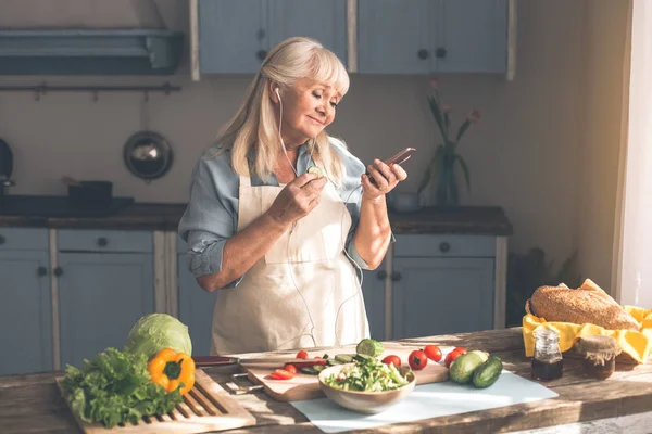 Ruhige Seniorin hört Musik in Küche — Stockfoto