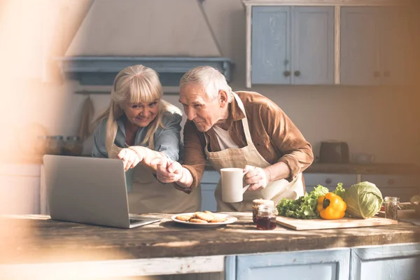 Joyful mogen man och hustru med laptop i cook rum — Stockfoto