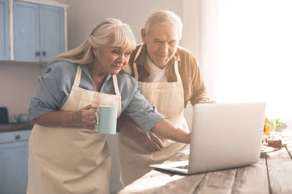 Joyful mogen man och hustru med dator i cook rum — Stockfoto