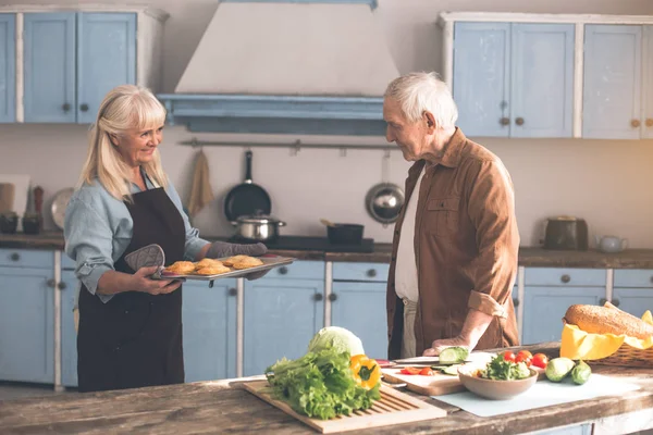 Vrolijke senior huisvrouw houden dienblad met gebak voor echtgenoot — Stockfoto