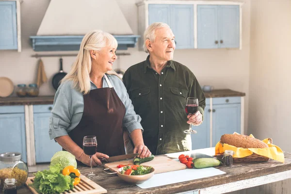 Emocionado esposa vieja cortando verduras cerca del marido en la sala de cocina — Foto de Stock