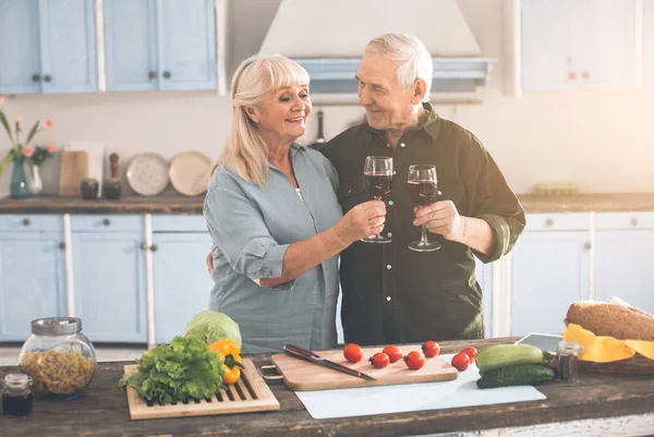 Gelukkig oud getrouwd koppel het drinken van wijn op kamer van de kok — Stockfoto