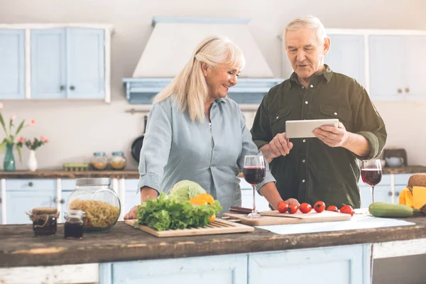 Счастливый пожилой мужчина и женщина выбирая рецепт на современном устройстве — стоковое фото