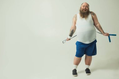 Halsiz şişman adam arkasından ip atlama tutmak