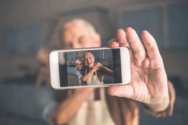 Радостная пожилая супружеская пара фотографирует себя на смартфон — стоковое фото