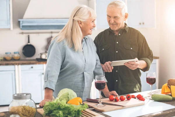 Веселые старший муж и жена с помощью планшета для приготовления пищи — стоковое фото