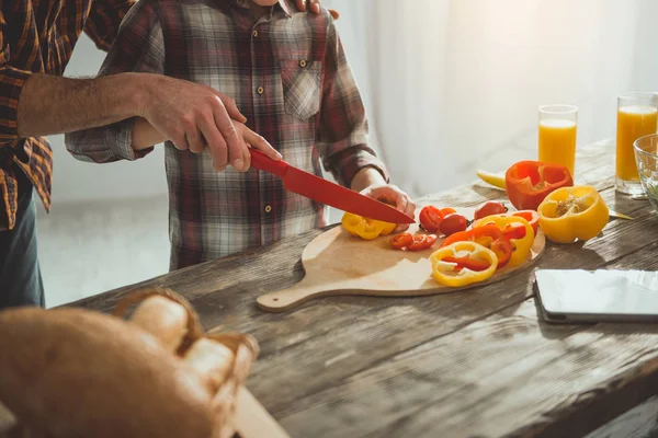 Pai e filho cortando legumes juntos — Fotografia de Stock