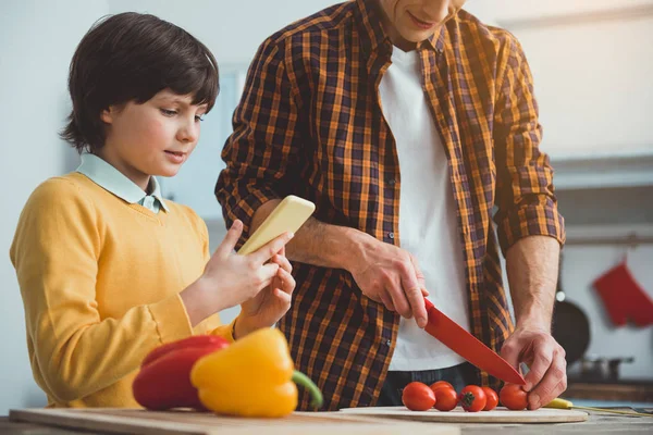 Parent and kid cooking according to online recipe — Stock Photo, Image