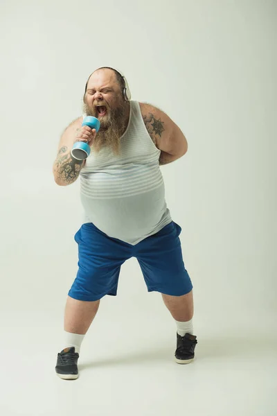 Волнующий толстый парень поет песню в спортивном весе — стоковое фото