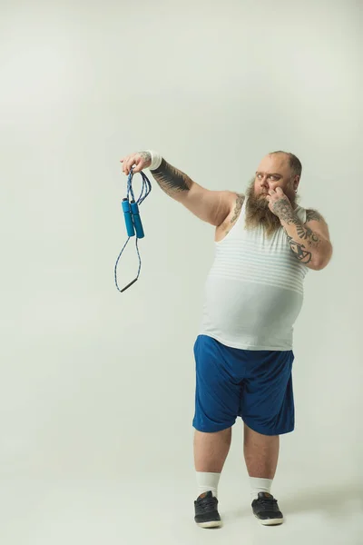 Hombre obeso mirando a saltar la cuerda con aversión — Foto de Stock