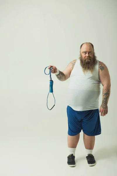 Hombre gordo perezoso sosteniendo una cuerda saltando — Foto de Stock