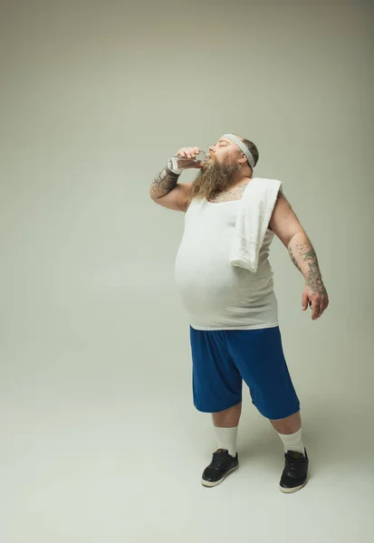 Hombre gordo cansado bebiendo agua de la botella después del deporte — Foto de Stock