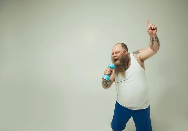 Hombre gordo inspirado realizando canción en el peso de los deportes — Foto de Stock
