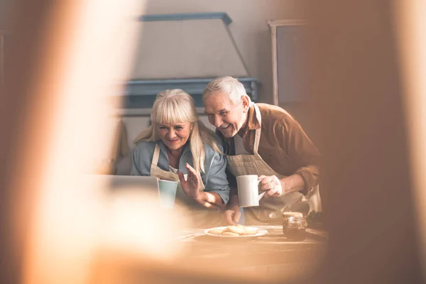 Glada senior man och kvinna hälsning familj av bärbara internet — Stockfoto