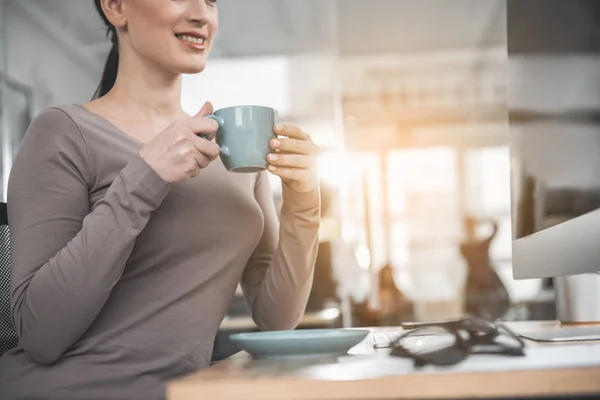 Mujer feliz degustación taza de café en el trabajo — Foto de Stock