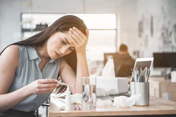 Triste señora enferma mirando el termómetro clínico — Foto de Stock