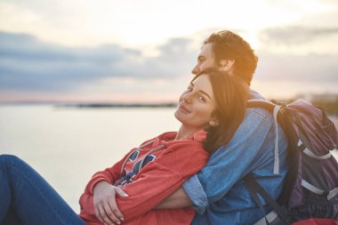 Memnun kız erkek arkadaşı ile birlikte doğanın keyfini portresi. Çift günbatımı deniz kenarında izlerken kucaklayan