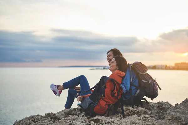 Couple heureux assis sur le rocher et regardant le coucher du soleil — Photo