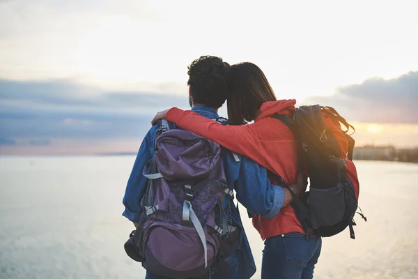 Homme et femme paisibles regardant le coucher du soleil au bord de la mer — Photo