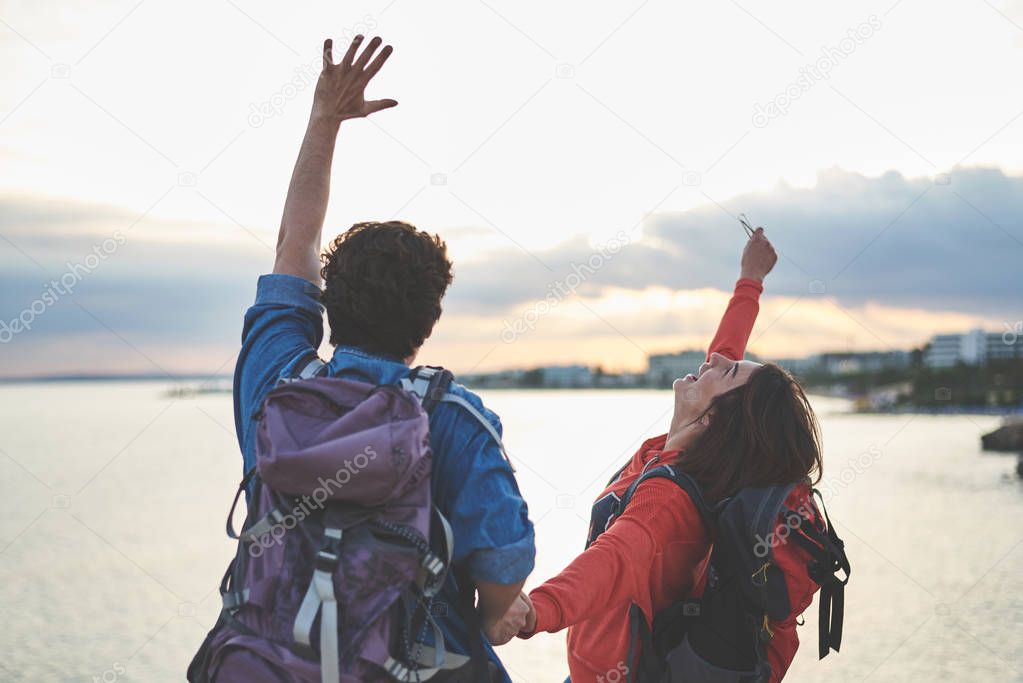 Happy couple of travelers standing near the sea