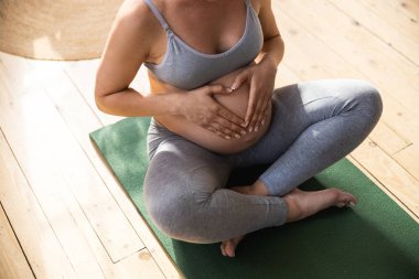 Young expectant mother sitting on exercise mat
