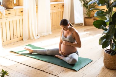 Happy young pregnant lady touching her belly