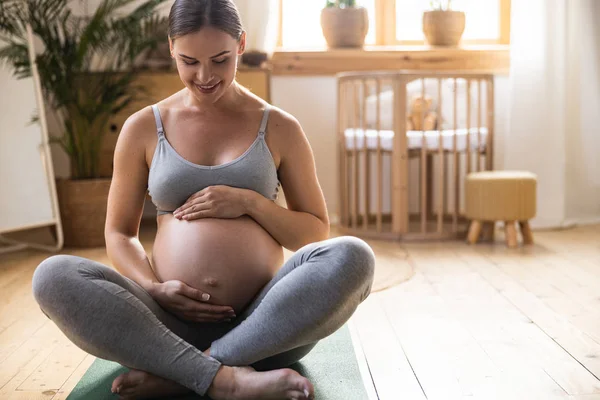 Усміхнена вагітна леді сидить на підлозі — стокове фото