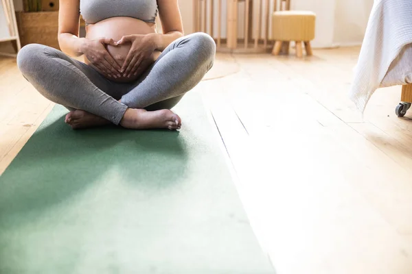 Expectant mother putting palms on her stomach — Stok fotoğraf