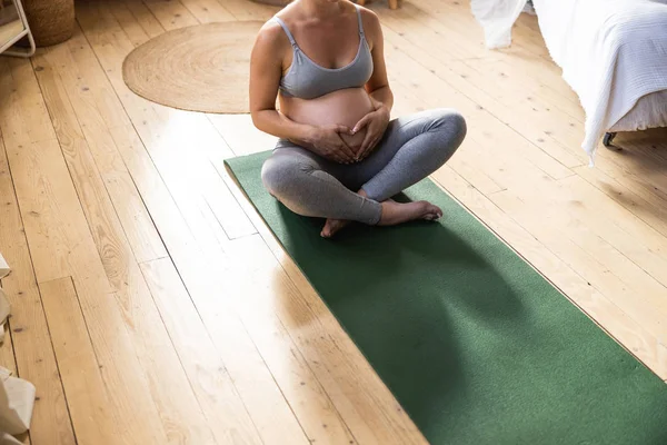 Pregnant woman resting on mat in room — Stok fotoğraf