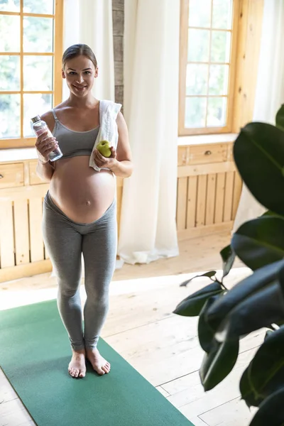 Pretty smiling pregnant lady holding water and apple — Stok fotoğraf