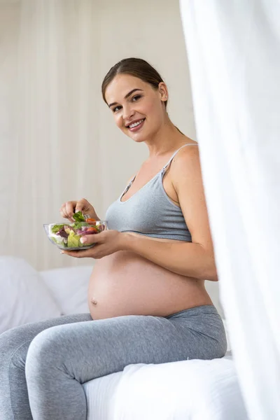 Jolie dame enceinte souriante tenant la salade à la main — Photo